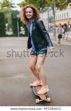 Outdoor shot of beautiful young woman on skateboard. Teenage girl enjoying skating outdoors.