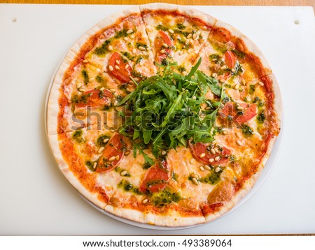 pizza with pine nuts, arugula and tomatoes