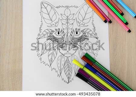 Adult anti stress coloring and soft tip pencils on wooden table, top view