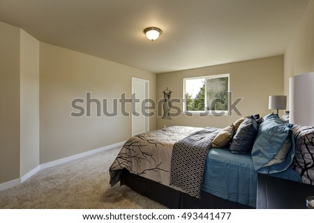 Simple design interior of beige Woman's bedroom on the second floor. There is large bed, two nightstands and soft carpet floor. Northwest, USA