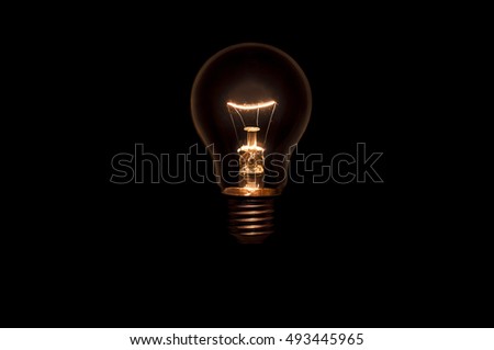 Tungsten light bulb without wiring and socket on black background. Concept for creative idea. Royalty-Free Stock Photo #493445965