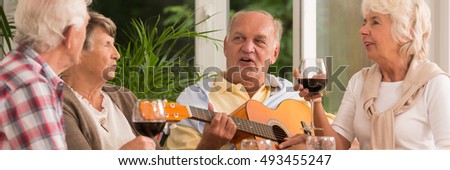 Elder man playing the guitar with his friends singing a song