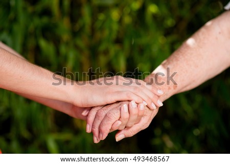 close up of young woman hand holding with tenderness an elderly senior person hands  