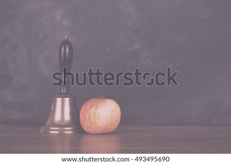 Old fashioned bell and an apple against a blackboard Vintage Retro Filter.