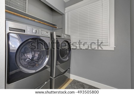 Laundry interior with gray walls, carpet, small window with jalousie and modern appliances. Northwest, USA