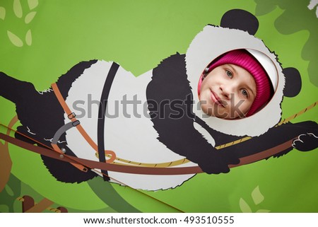 Girl poses inserting his face into hole in climbing panda shape.