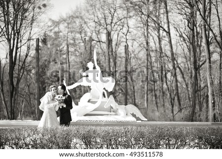 Black and white picture of wedding couple posing before white fountain
