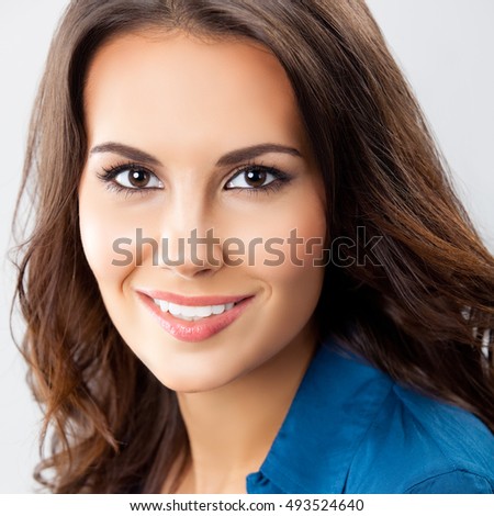 Portrait of happy smiling young cheerful businesswoman, over grey background. Caucasian brunette model in business concept studio shoot. Square composition.