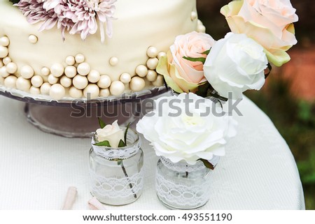 A picture of a wedding cake and roses standing on the table next to it