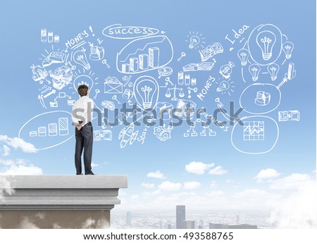 Rear view of businessman standing on the roof of skyscraper. Chalk startup sketch is drawn in the sky. Concept of business founder