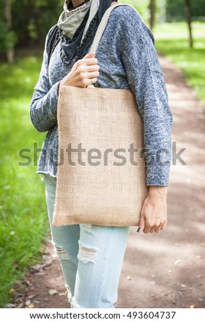 Woman holding empty canvas bag outdoor. Template mock up