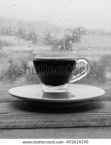 cup of coffee espresso on wooden table next to window. black and white