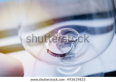 Wedding rings stacked on a glass of champagne.