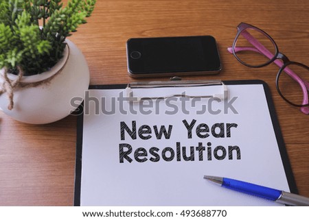 New Year Resolution word written on paper with glass, smartphone and green plant, copyspace area
