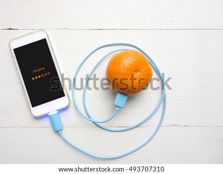 Smartphone charging battery from orange fruit, Smart and Eco - Friendly to Charge Smartphone concept.