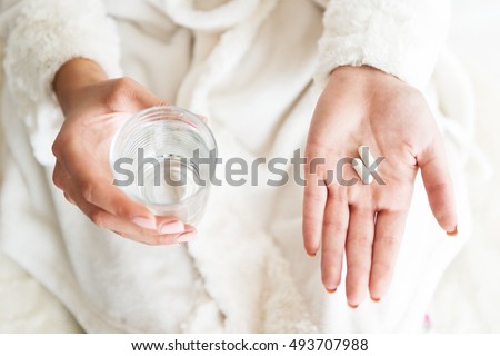 Woman holding a glass of water and pills, detail   Royalty-Free Stock Photo #493707988