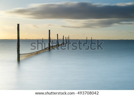 Long exposure picture of a fyke at the IJsselmeer with the skyline of Amsterdam in the background.