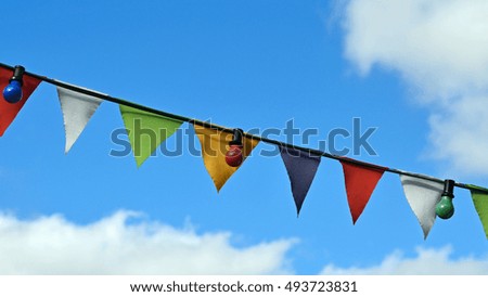 colorful small triangle flags with lampions waving in the blue cloudy sky
