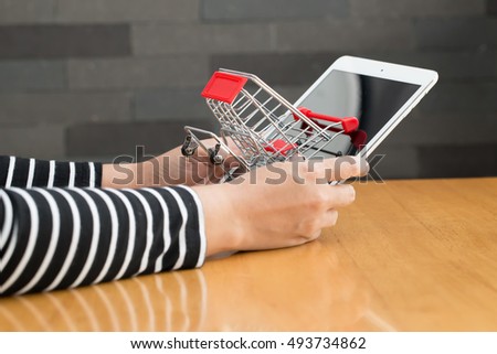 Online shopping concept, Woman hand holding tablet and shopping cart