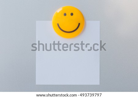 Yellow magnet clip on paper note, abstract background.