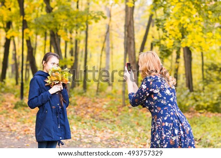 Mother making photos of her daughter child outdoor.