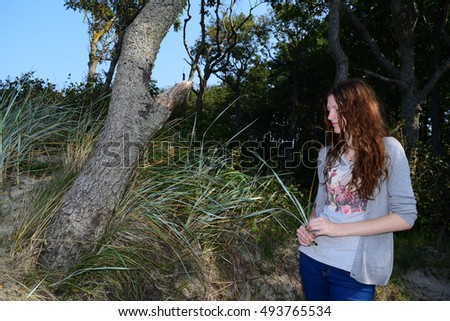 Beautiful girl with long hair standing near a tree on the nature