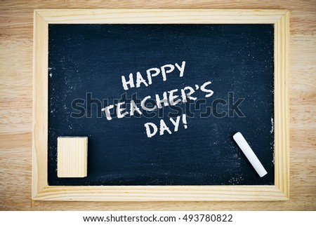 Happy Teacher's Day.. Blackboard with Happy Teacher's Day sign, white chalk and duster on wooden background