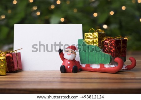 Christmas concept, toy santa sleigh, pine tree and gift boxes on wooden floor and blur green and light bokeh