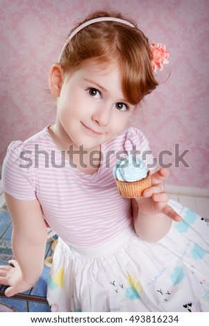 Portrait of lovely little girl smiling with cupcake looking at camera. 
