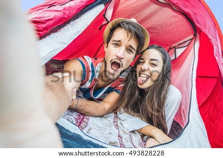 Camping couple in tent taking selfie. Happy friends having fun togheter. Concept about people, lifestyle and technology