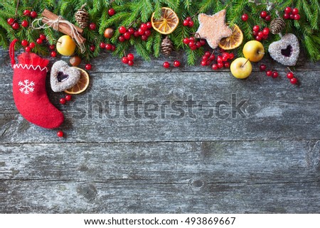 Christmas wooden background with branches of trees, apples, berries, cakes and socks