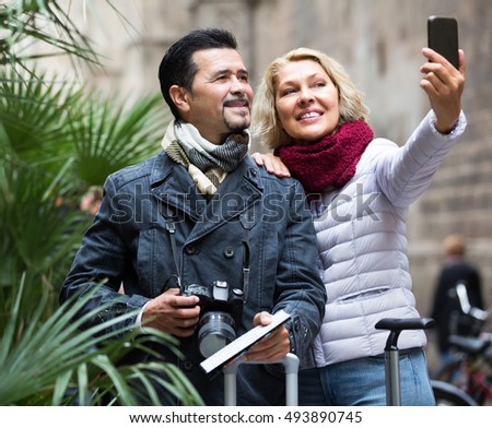 Elderly  positive tourists taking selfie on smartphone camera and smiling