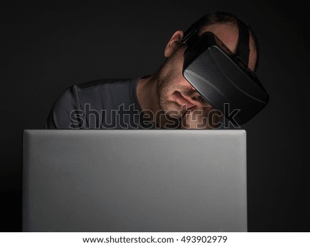 Tired addicted man to technology  using virtual reality headset at night. Technology addiction and mental disorders concept.