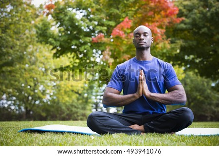 young black man wearing athletic wear sitting in the park exercising yoga Royalty-Free Stock Photo #493941076