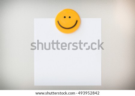Yellow magnet clip on paper note on gray refrigerator background for input text.