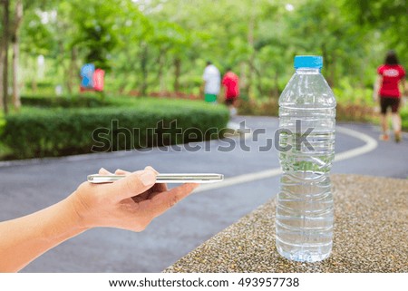 Man use mobile phone, blur image of people exercise in the park as background.