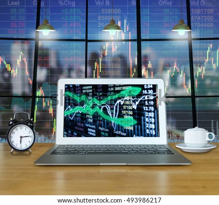 Workspace with computer laptop on the wood table which shown stock market exchange on the screen with trading graph over the cityscape building background, business trading technology concept