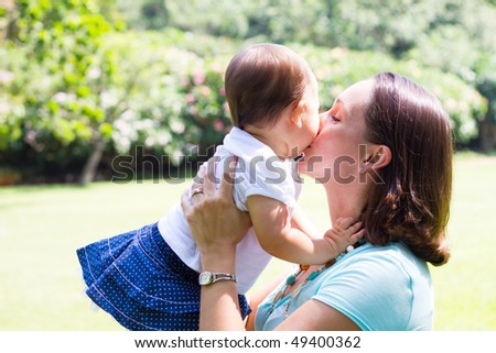 happy mother kissing daughter outdoors
