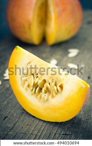 Autumn pumpkin with pumpkin seeds on old rustic wooden background. Thanksgiving Halloween Autumn holidays background concept. Selective focus.