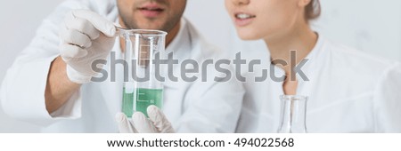 Couple of students in white lab coats looking at the beaker with product of experiment