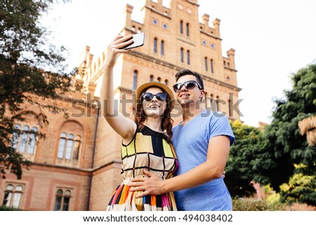 Happy couple of tourists taking selfie in old city