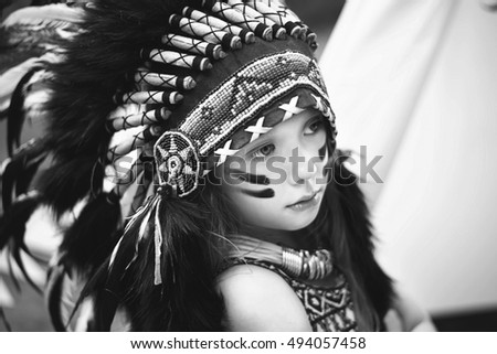 Black and white portrait. Girl in indian costume with roach wearing on her head, wigwam tent at background