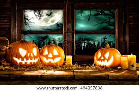 Scary halloween pumpkins on wooden planks, placed in front of window with scary background