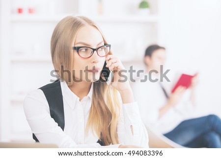 Closeup portrait of gorgeous caucasian girl with blonde hair, wearing formal outfit and talking on mobile phone