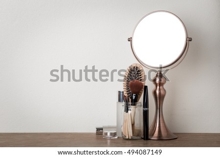 vintage metal mirror and make up set on wooden table.