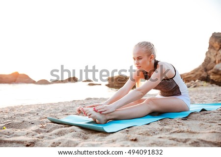 Portrait of a young woman stretching on yoga mat outdoors