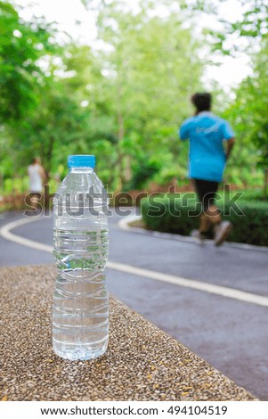 The bottle of water on the bench ,blur image of people exercise in the park as background.