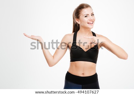 Happy fitness woman pointing finger at copyspace on her palm isolated on a white background
