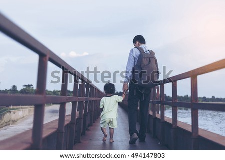 Happy family - father holds baby daughter holding hands, walk with fun along sunset  on bridge. Travel, active parents lifestyle, people activity on summer vacations with children.