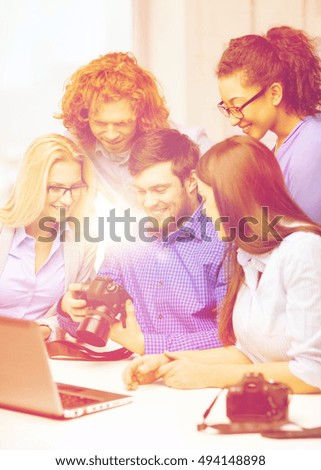 business, office and startup concept - smiling creative team with laptop computer and photocamers working in office